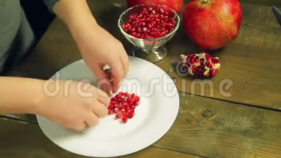 女人的手在一个白色的盘子里从石榴籽里伸出来视频的预览图