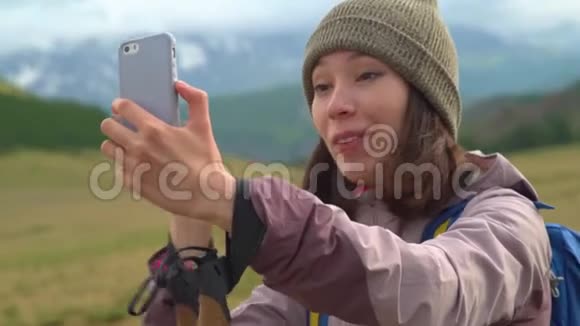 一个年轻的女人在山上自拍一个漂亮可爱的阿桑旅游女孩用手机自拍照片视频的预览图