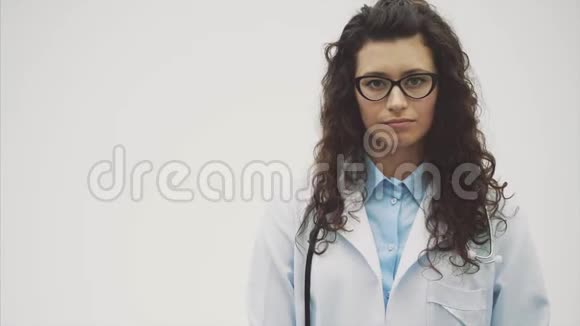年轻漂亮的女医生在这段时间里它是在一个灰色的背景上并保持音筒在颈部期间视频的预览图