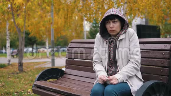 一个穿着帽衫的年轻女人在秋天公园打喷嚏和鼻涕视频的预览图