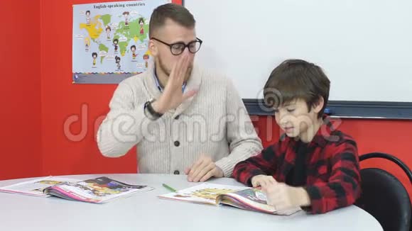快乐的老师和男孩在学校的教室里高五视频的预览图