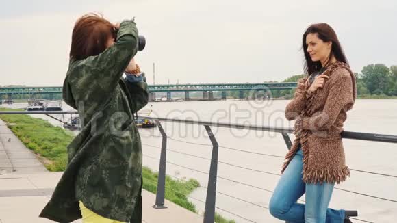 布鲁内特拿着相机在女人面前摆姿势视频的预览图