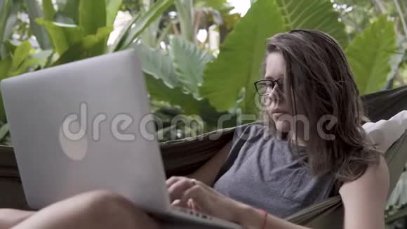 女人在吊床上用笔记本电脑视频的预览图