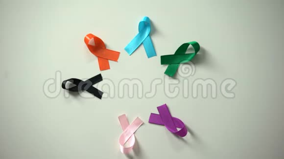 男性和女性的双手在桌子上放置五颜六色的丝带世界癌症日视频的预览图