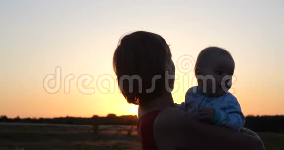 美丽的女人带着一个孩子在夕阳下欣赏闪闪发光的乡村景色视频的预览图