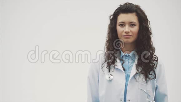 年轻漂亮的女医生在这段时间里它是在一个灰色的背景上并保持音筒在颈部期间视频的预览图