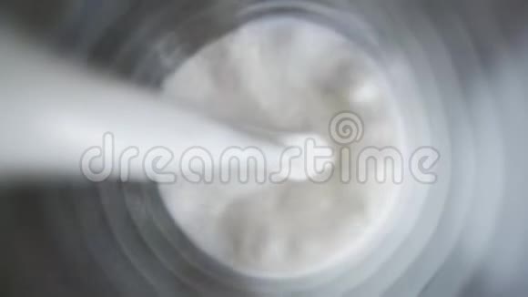 在深色桌子上的玻璃杯中倒入牛奶的俯视图接近倒入牛奶的俯视图视频的预览图