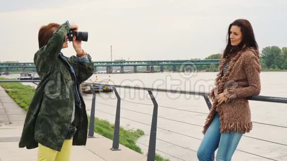布鲁内特拿着相机在女人面前摆姿势视频的预览图