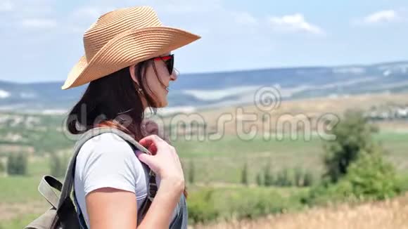 戴着帽子和太阳镜的年轻背包女子侧视图欣赏令人惊叹的自然景观视频的预览图