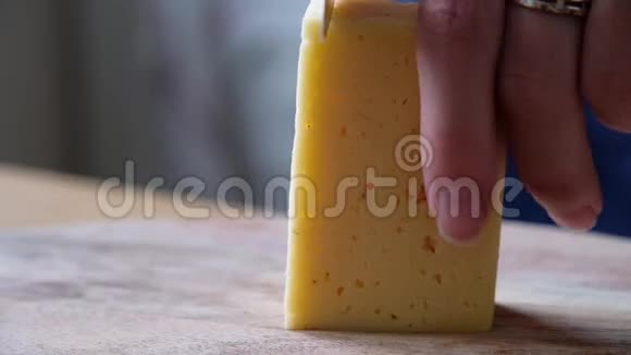 一位中年厨师在木板上用刀切奶酪的宏观部位特别靠近视频的预览图
