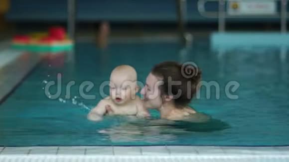 妈妈和宝宝在游泳池里游泳玩得开心笑得开心加速录像回放婴儿健康生活方式视频的预览图