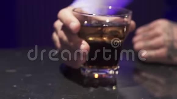 男的手把装有冰块的酒精液体放在黑桌上视频的预览图