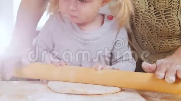一家人做小馅饼一个小女孩在奶奶的帮助下把面团卷出来视频的预览图