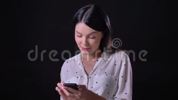 迷人的年轻黑发女人打电话站在黑色背景孤立微笑的相机视频的预览图