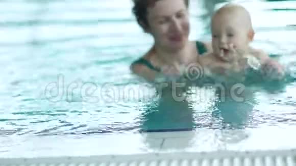 宝宝和妈妈正在室内水池边的水里游泳一年以下婴儿的发育视频的预览图