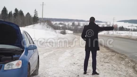 男子乘坐硬纸板在冬季乡村道路搭便车视频的预览图