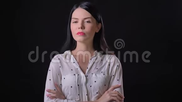 穿着衬衫双手交叉思考站在黑色背景上的年轻黑发女人视频的预览图