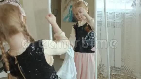 穿着粉红色裙子扎着辫子的开朗女孩试着穿着成年妈妈衣服连衣裙高跟鞋和在前面跳舞视频的预览图