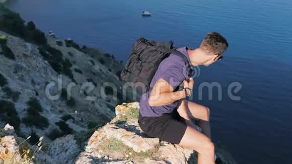 多利射中男性背包客坐在悬崖上俯视高空视频的预览图