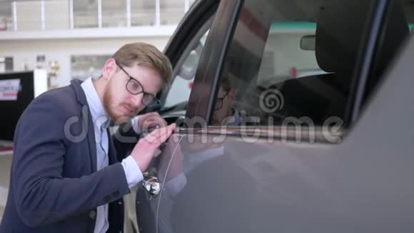 汽车商店年轻的客户男性进入眼镜与高兴抚摸新汽车轻轻微笑的经销商视频的预览图
