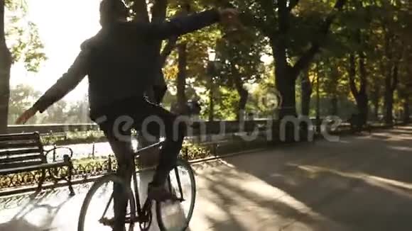 带着耳机的年轻人骑着自行车在公园里徒步旅行的黑色自行车边听边骑马和跳舞视频的预览图