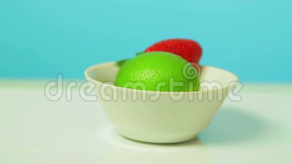 青柠色的水果和成熟的草莓浆果放在白色的盘子里旋转成一圈视频的预览图