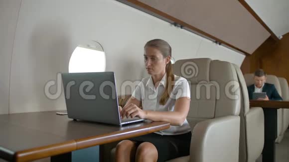 女商人在飞机上用笔记本电脑视频的预览图