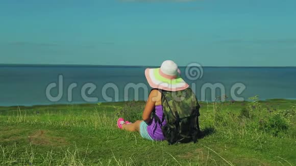一个背着背包戴草帽的女人坐在山上欣赏下面的湖从视频的预览图