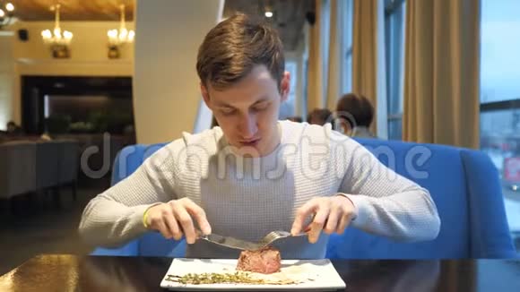 年轻人下班后用刀叉在咖啡馆里吃美味的牛排视频的预览图