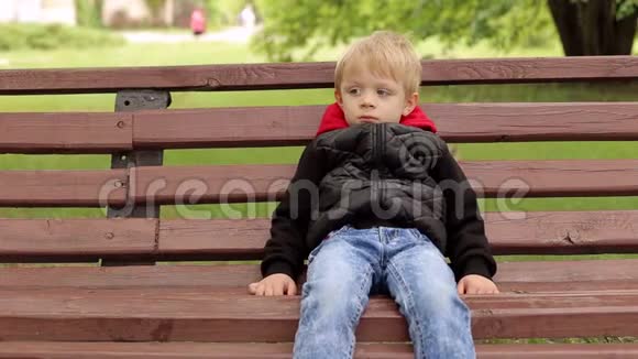 公园里一个悲伤的男孩在长凳上的肖像视频的预览图