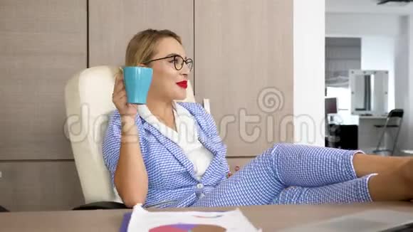 金发成功的女商人在办公桌前放松双脚放在桌子上视频的预览图