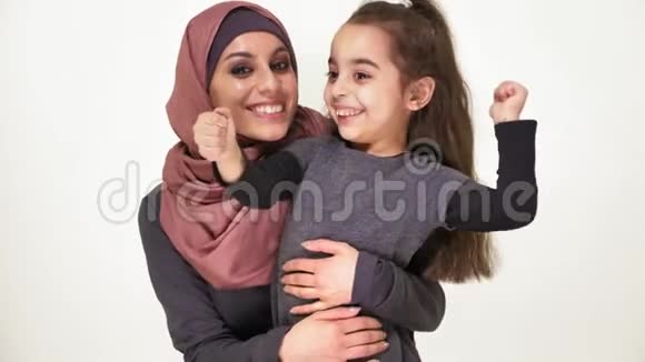 年轻漂亮的母亲戴着头巾拥抱着她的小女儿笑着说家庭幸福的家庭观念等等看镜头视频的预览图