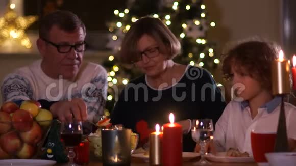 新年的背景下一家人在烛光庆祝圣诞节爷爷把沙拉放在他的视频的预览图
