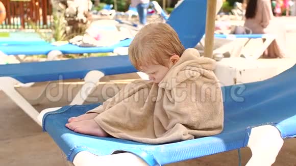 悲伤的小男孩坐在海滩上的懒汉身上视频的预览图