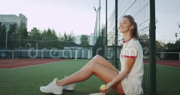 一个漂亮的女士特写坐在网球场的地板上打和缓存网球视频的预览图