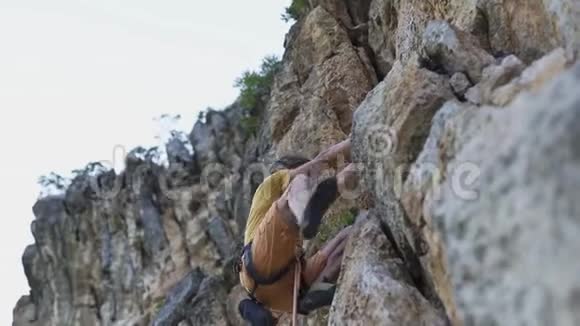 年轻的攀岩者开始在悬崖上攀岩寻找伸手抓住视频的预览图
