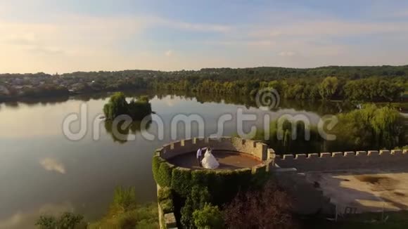 靠近城堡和水的新娘和新郎的鸟瞰图视频的预览图