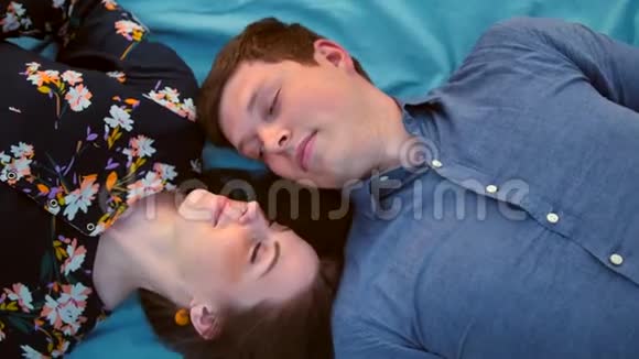 幸福的年轻夫妇躺在草地上日落微笑和欢笑视频的预览图