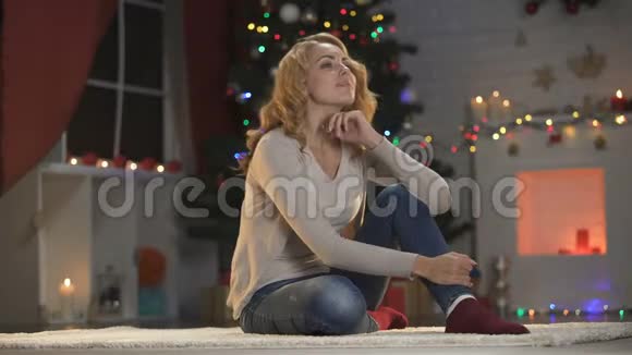 坐在圣诞树旁的美女对着镜头微笑装饰着视频的预览图