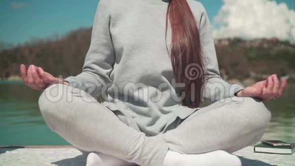 春天的一天一位年轻女子坐在湖边的木墩上在阳光下冥想在大自然中放松视频的预览图