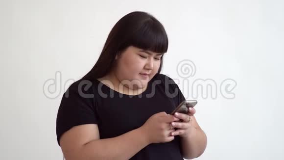 一位20岁的胖美亚洲女人的肖像在白色背景下在电话中有感情地聊天视频的预览图