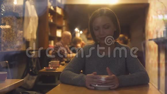 迷人的女人在舒适的咖啡屋里休息喝热味饮料视频的预览图