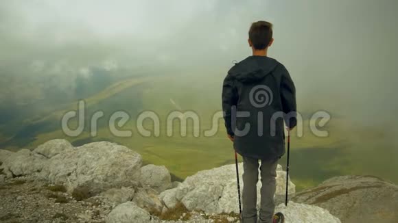 一个无忧无虑自由自在的男孩抬起手望着天空年轻的背包客爬上了山顶视频的预览图