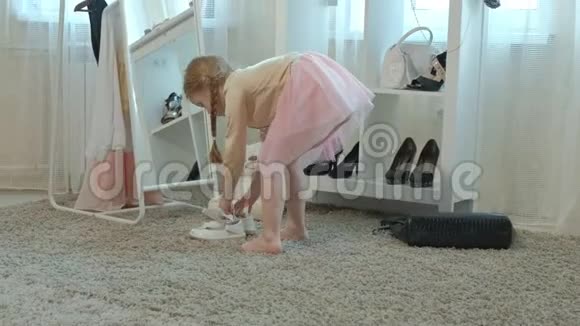 穿着粉红色裙子扎着辫子的开朗的小女孩穿着妈妈高跟鞋在镜子前跳舞视频的预览图