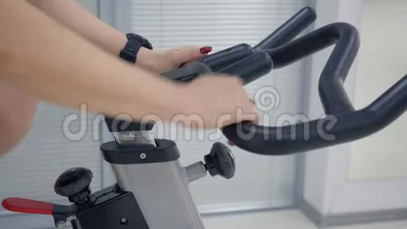 健身女性手握手柄室内自行车调整训练视频的预览图