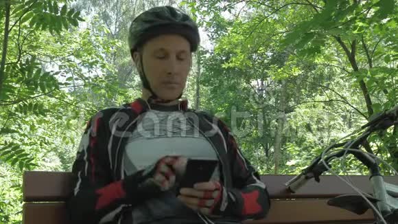 男运动员平均年龄训练后在公园的长凳上休息他用的是智能手机视频的预览图