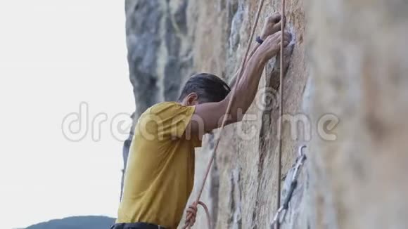 年轻的攀岩者开始在悬崖上攀岩寻找伸手抓住视频的预览图