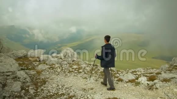一个无忧无虑自由自在的男孩抬起手望着天空年轻的背包客爬上了山顶视频的预览图