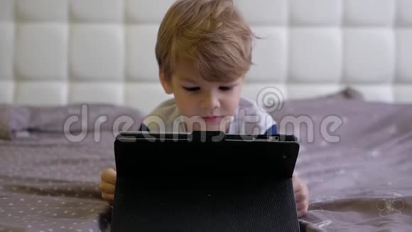 男孩躺在床上看着平板电脑视频的预览图
