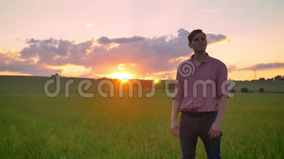 年轻人和老农民握手站在麦田里在背景下观看美丽的日落视频的预览图